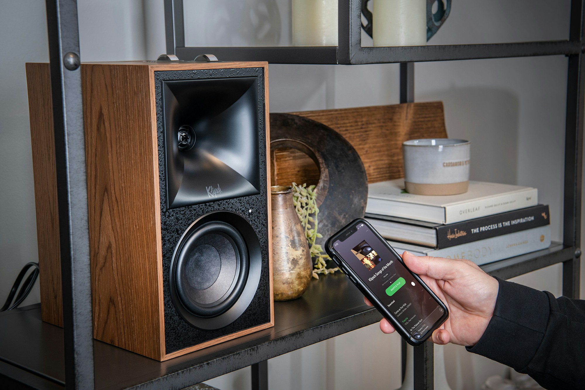 Klipsch The Fives Powered speaker monitors on a shelf with phone